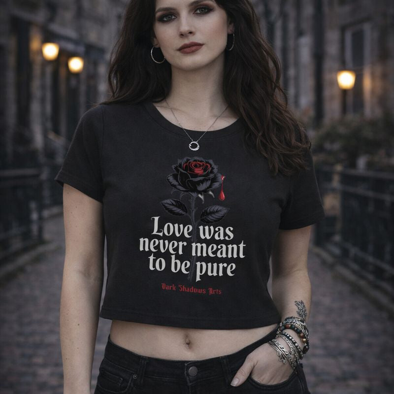 Schwarzes enganliegendes Ladies Cropped Tee mit Dark Romantic Motiv „Love Was Never Meant to Be Pure“, schwarze Rose mit rotem Tropfen und Gothic Statement, getragen von Model im urbanen Gothic Street-Setting, Design von Dark Shadows Arts