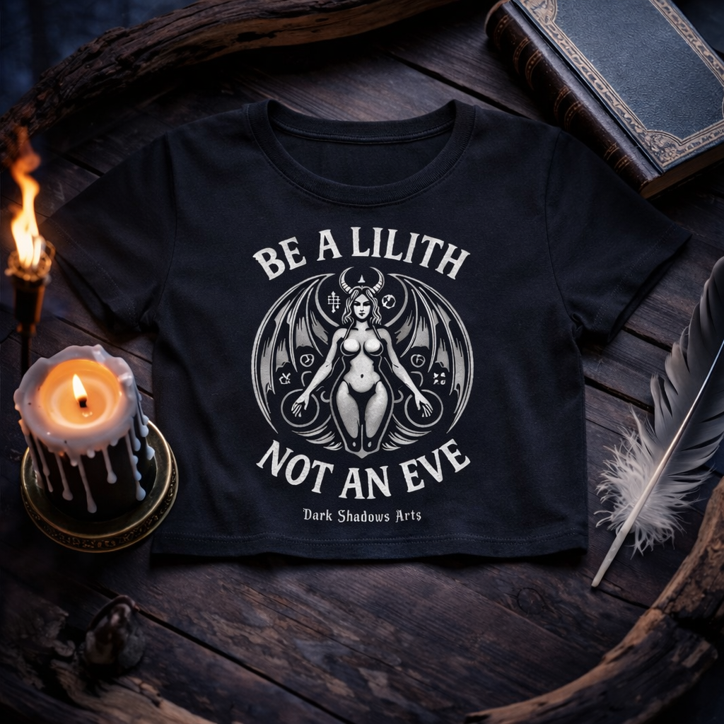 Lilith – Die Urfigur der Nacht Ladies Cropped Tee von Dark Shadows Arts im 1:1 Gothic Mockup mit Kerze, Feder und antikem Buch auf dunklem Holztisch