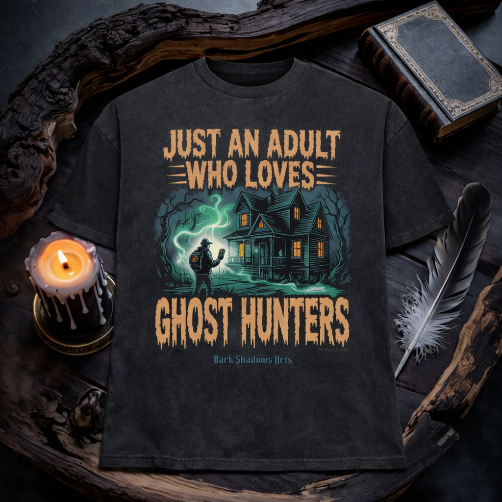 Just an Adult Who Loves Ghost Hunters Heavy Cotton Oversized Shirt von Dark Shadows Arts im düsteren Flatlay Mockup mit Kerzenlicht, altem Buch und mystischer Atmosphäre – Haunted House und Ghost Hunter Motiv auf charcoal grauem Oversized Shirt